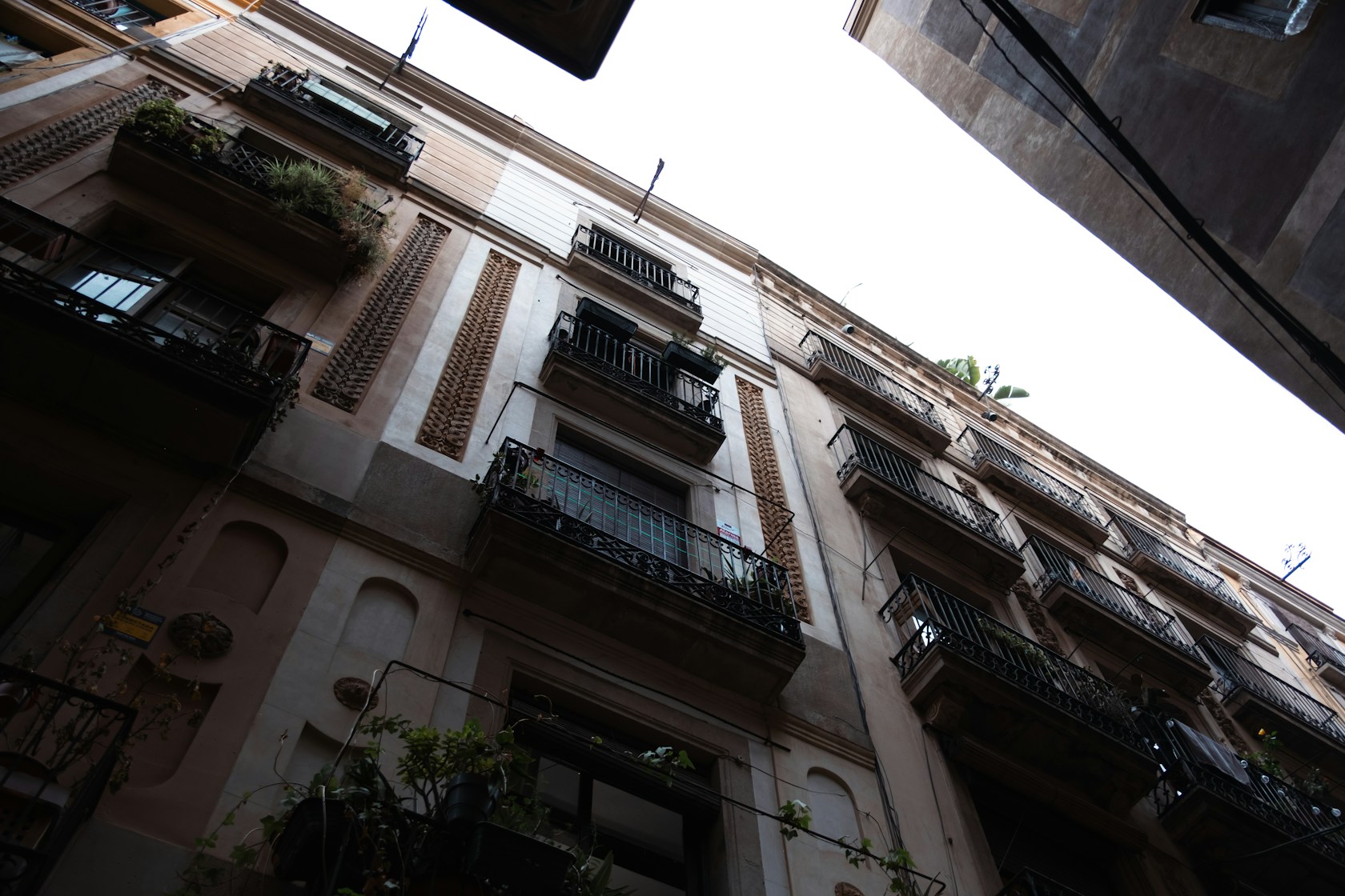 Vista hacia arriba de edificios de viviendas con balcones de hierro en Barcelona