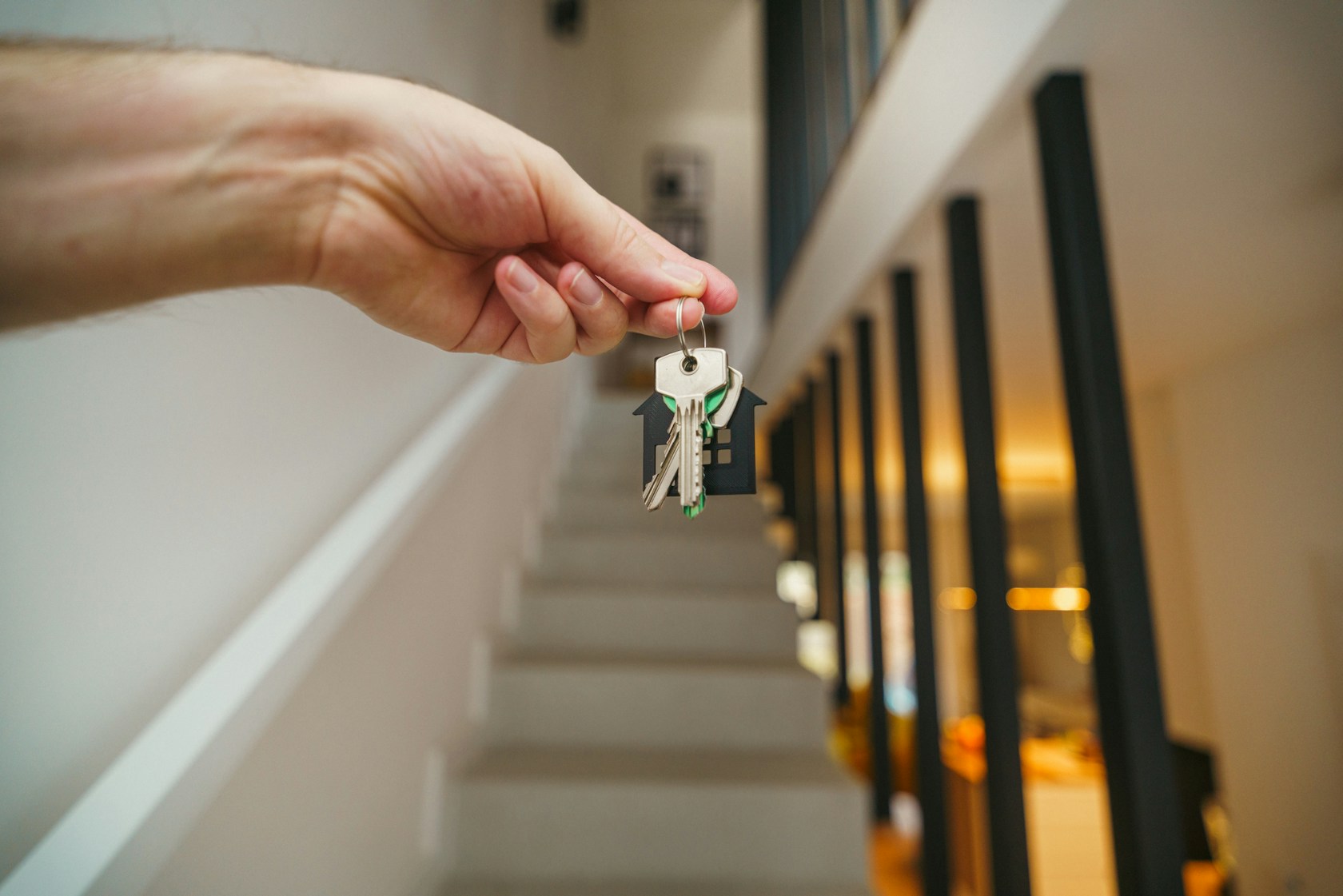 Mano sosteniendo las llaves de una casa nueva con llavero en forma de casa