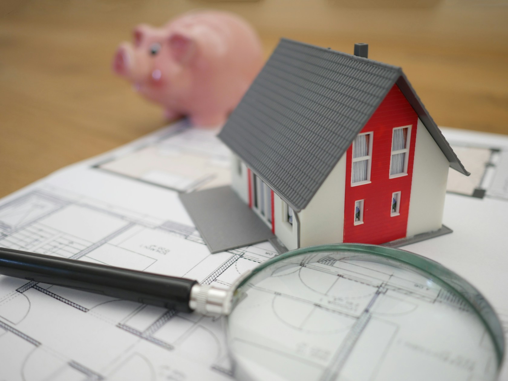 Bonificaciones de la hipoteca: maqueta de casa, lupa y planos para revisar las condiciones del préstamo
