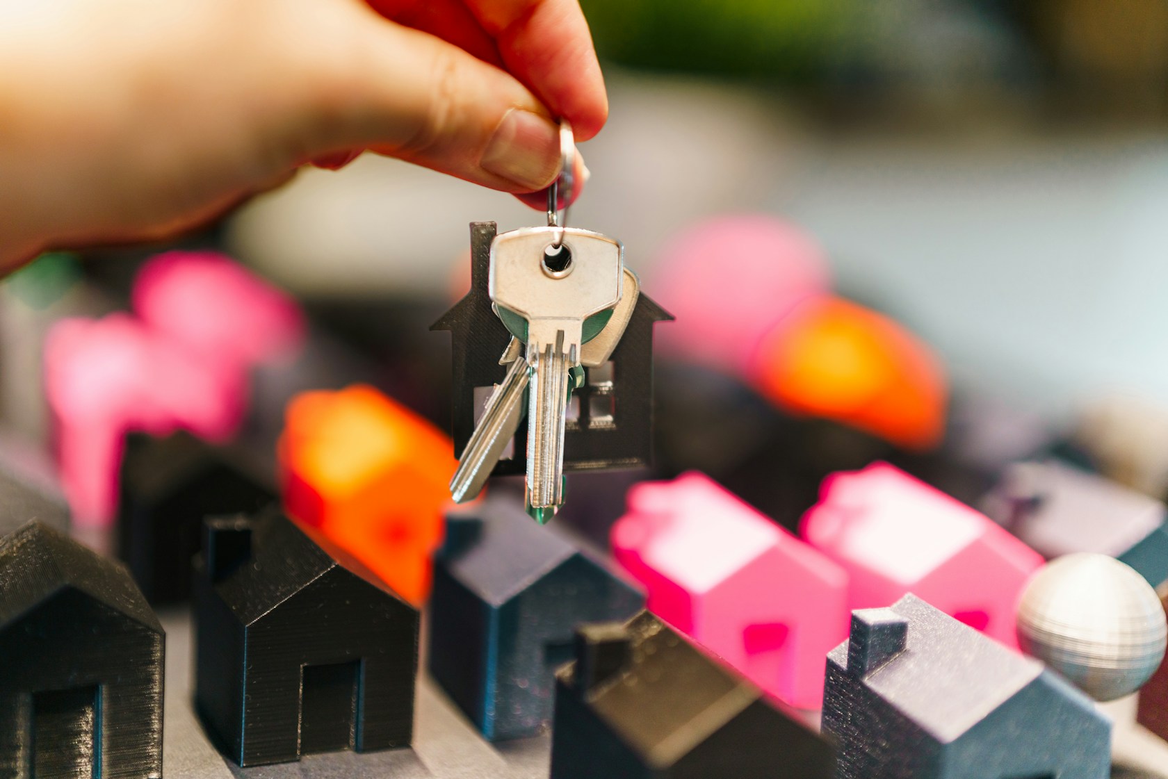 Euríbor 2026: mano sosteniendo las llaves de una vivienda sobre maquetas de casas, símbolo de la hipoteca variable
