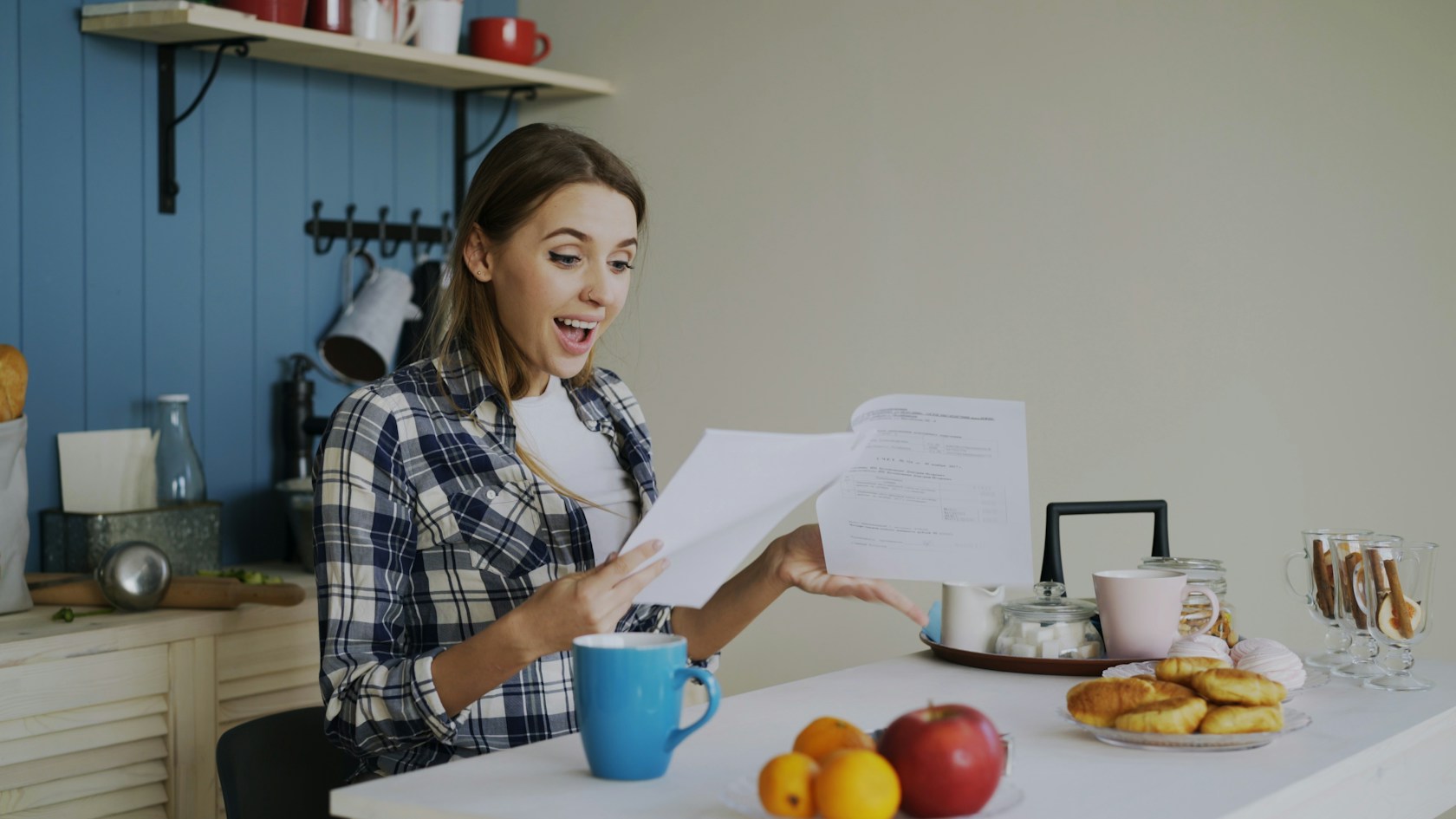 Hipoteca con contrato temporal: mujer joven revisando en la cocina la documentación de su solicitud de hipoteca