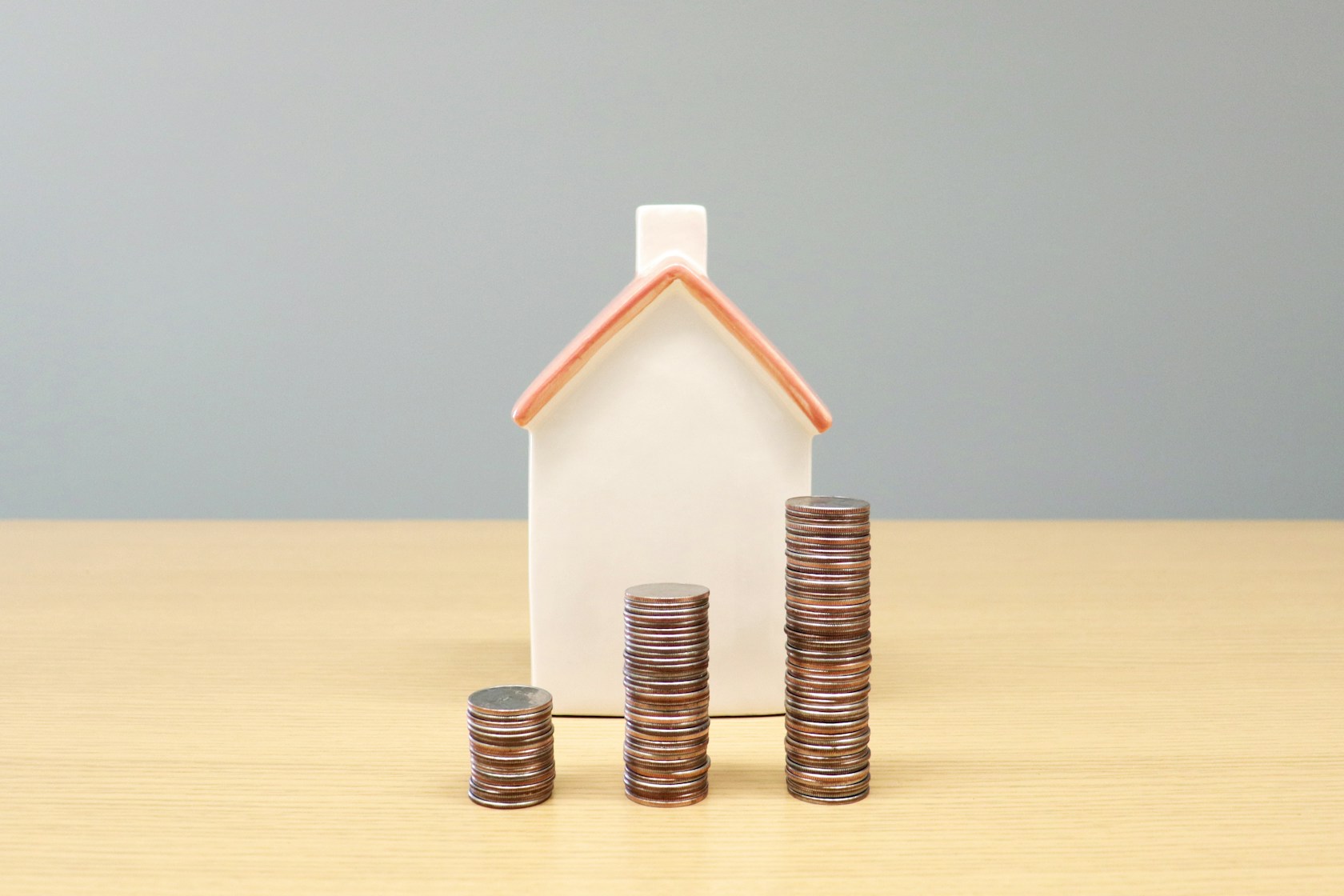 No puedo pagar la hipoteca: maqueta de una casa junto a tres montones de monedas sobre una mesa